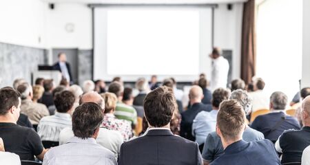 I have a question. Group of business people sitting at the chairs in conference hall. Businessman standing up asking a question. Conference and Presentation. Business and Entrepreneurship.の写真素材