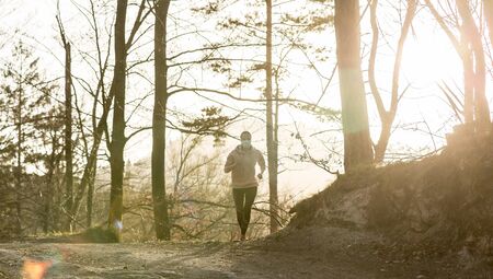 Portrait of caucasian sporty woman wearing a medical protection face mask while running in nature....