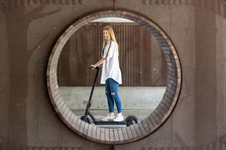 Casual caucasian teenager riding urban electric scooter in urban environment. Urban mobility...