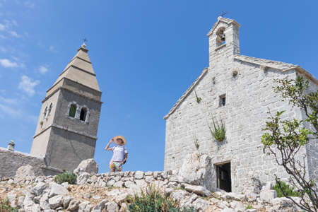 Female traveler sightseeing in an ancient costal village of Lubenice on the island of Cres, Croatia.