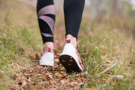 Rear close up view of female step on nature track. Young woman hiking in nature. Adventure, sport and exercise concept.の写真素材