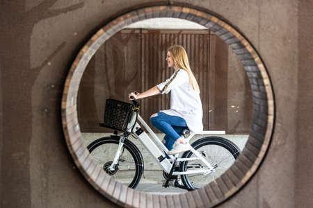 Casual caucasian teenager riding urban electric bicycle in urban environment. Urban mobility...