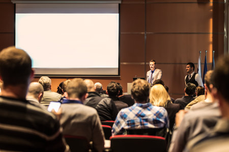 Speaker giving a talk in conference hall at business meeting event. Rear view of unrecognizable people in audience at the conference hall. Business and entrepreneurship concept.の写真素材
