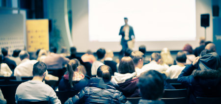 Speaker giving a talk in conference hall at business event. Rear view of unrecognizable people in audience at the conference hall. Business and entrepreneurship concept.の写真素材