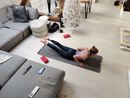 Beautiful blonde woman doing home workout indoors. Woman practice yoga at home. Fit girl using...