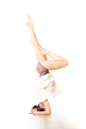 Portrait of active sporty young woman practicing standing on head yoga pose in yoga studio. Healthy active lifestyleの写真素材