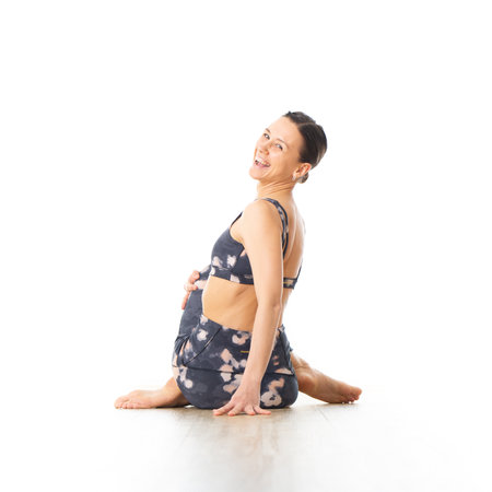 Rear view of young sporty female yoga instructor in bright white yoga studio, smiling cheerfully...