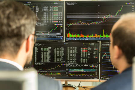 Stock brokers looking at computer screens, trading online.
