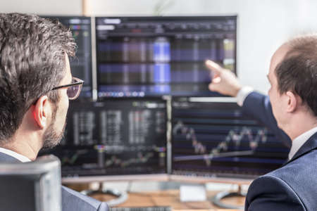 Stock brokers looking at computer screens, trading online.の写真素材