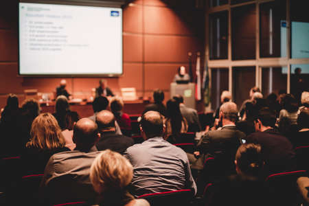 Audience in lecture hall participating at business event.