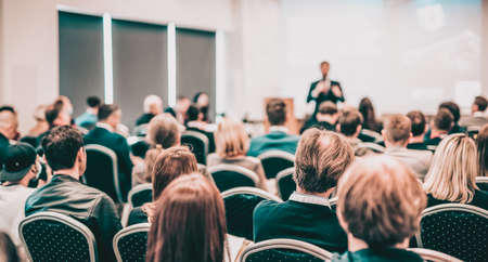 Speaker giving a talk in conference hall at business event. Rear view of unrecognizable people in audience at the conference hall. Business and entrepreneurship concept.の写真素材