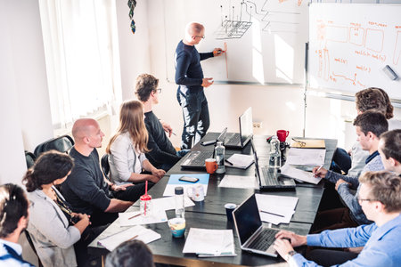Informal IT business startup company meeting. Team leader discussing and brainstorming new project and ideas with colleagues. Startup business and entrepreneurship conceptの写真素材