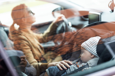 Mother concentrating on driving family car running errands while her baby sleeps in infant car seat...
