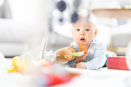 Cute baby boy playing with hanging toys arch on mat at home Baby activity and play center for early infant development. Baby playing at homeの写真素材