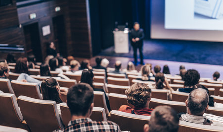 Speaker giving a talk in conference hall at business event. Rear view of unrecognizable people in audience at the conference hall. Business and entrepreneurship conceptの写真素材