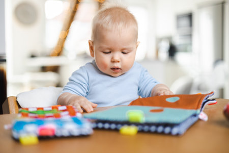 Happy infant sitting at dining table and playing with his toy in traditional scandinavian designer wooden high chair in modern bright atic home. Cute baby playing with toys.の写真素材