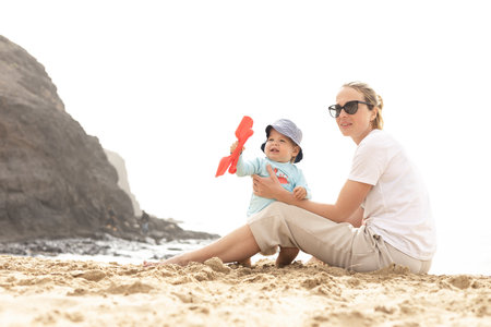 Mother playing his infant baby boy son on sandy beach enjoying summer vacationson on Lanzarote island, Spain. Family travel and vacations conceptの写真素材