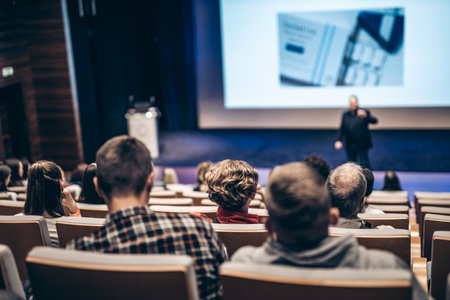 Speaker giving a talk in conference hall at business event. Rear view of unrecognizable people in audience at the conference hall. Business and entrepreneurship conceptの写真素材