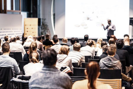 Speaker giving a talk in conference hall at business event. Audience at the conference hall. Business and Entrepreneurship concept. Focus on unrecognizable people in audience.の写真素材