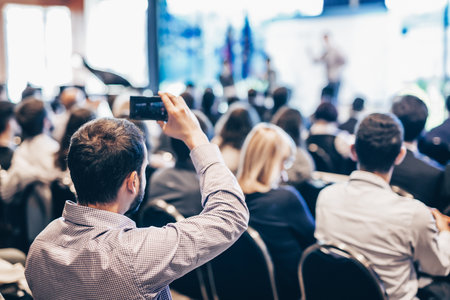 Speaker giving a talk in conference hall at business event. Rear view of unrecognizable people in audience at the conference hall. Business and entrepreneurship conceptの写真素材
