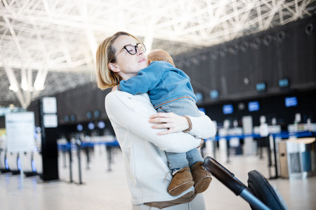 Motherat happily holding and lifting his infant baby boy child in the air after being rejunited in front of airport terminal station. Baby travel conceptの写真素材