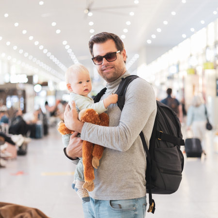 Father traveling with child, holding his infant baby boy at airport terminal waiting to board a plane. Travel with kids conceptの写真素材