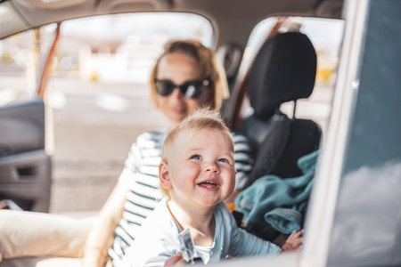 Mother and her infant baby boy child on family summer travel road trip, sitting at dads front seat, waiting in the car for father to buy farry ticketsの写真素材