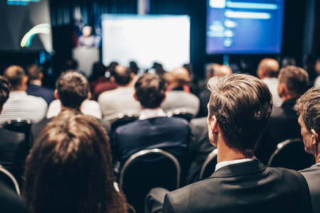 Speaker giving a talk in conference hall at business event. Rear view of unrecognizable people in audience at the conference hall. Business and entrepreneurship conceptの写真素材