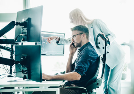 Stock broker business team trading online watching charts and data analyses on multiple computer screens in modern corporate work station officeの写真素材