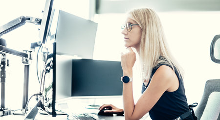 Female financial assets manager, trading online, watching charts and data analyses on multiple computer screens. Modern corporate business woman conceptの写真素材