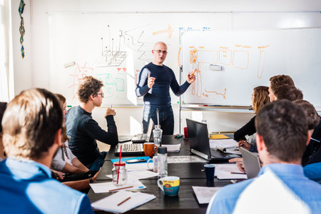 Informal IT business startup company meeting. Team leader discussing and brainstorming new approaches and ideas with colleagues. Startup business and entrepreneurship concept.の写真素材