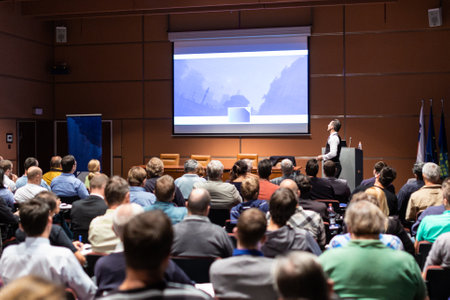 Speaker giving a talk in conference hall at business meeting event. Rear view of unrecognizable people in audience at the conference hall. Business and entrepreneurship concept.の写真素材