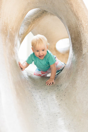 Child playing on outdoor playground. Toddler plays on school or kindergarten yard. Active kid on stone sculpured slide. Healthy summer activity for children. Little boy climbing outdoorsの写真素材