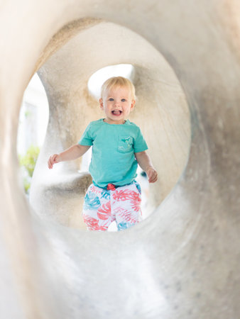 Child playing on outdoor playground. Toddler plays on school or kindergarten yard. Active kid on stone sculpured slide. Healthy summer activity for children. Little boy climbing outdoorsの写真素材