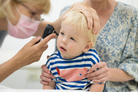 Infant baby boy child being examined by his pediatrician doctor during a standard medical checkup in presence and comfort of his mother. National public health and childs care care konceptの写真素材