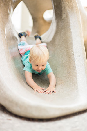 Child playing on outdoor playground. Toddler plays on school or kindergarten yard. Active kid on stone sculpured slide. Healthy summer activity for children. Little boy climbing outdoorsの写真素材