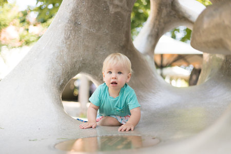 Child playing on outdoor playground. Toddler plays on school or kindergarten yard. Active kid on stone sculpured slide. Healthy summer activity for children. Little boy climbing outdoorsの写真素材