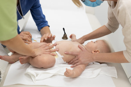 Baby beeing vaccinated by pediatrician in presence of his mother. Preventive vaccination against Diphtheria, whooping cough, tetanus, hepatitis, haemophilus influenzae, pneumococcus, poliomyelitis.の写真素材