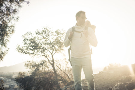 Young father carrying his infant baby boy son in backpack while tracking around Malaga, Spain in sunset. Family travel and vacation concept.の写真素材