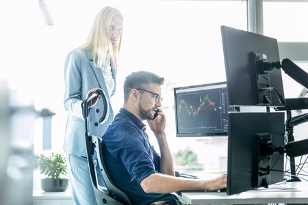 Stock broker business team trading online watching charts and data analyses on multiple computer screens in modern corporate work station officeの写真素材