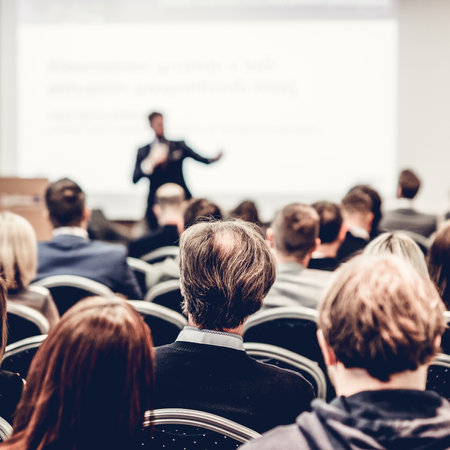 Speaker giving a talk in conference hall at business event. Rear view of unrecognizable people in audience at the conference hall. Business and entrepreneurship conceptの写真素材