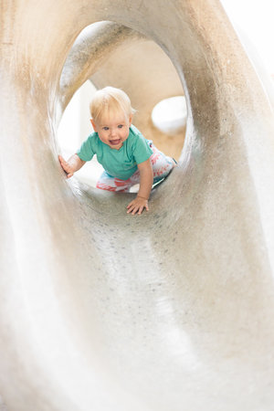 Child playing on outdoor playground. Toddler plays on school or kindergarten yard. Active kid on stone sculpured slide. Healthy summer activity for children. Little boy climbing outdoorsの写真素材