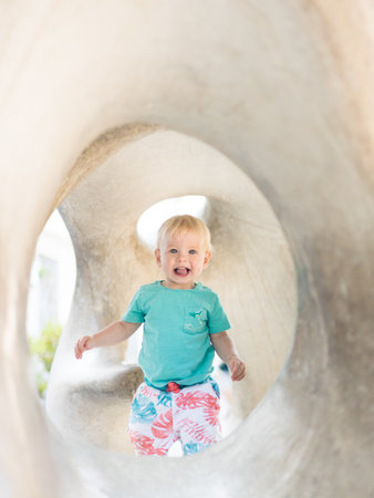 Child playing on outdoor playground. Toddler plays on school or kindergarten yard. Active kid on stone sculpured slide. Healthy summer activity for children. Little boy climbing outdoorsの写真素材