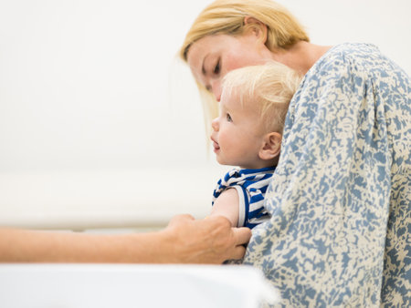 child beeing vaccinated by pediatrician in presence of his mother. Preventive vaccination against Diphtheria, whooping cough, tetanus, hepatitis, haemophilus influenzae, pneumococcus, poliomyelitis.の写真素材
