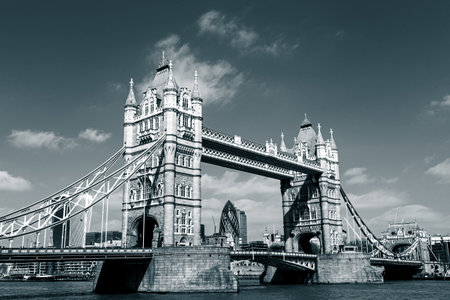 Red traditional double-decker bus driving on Tower Bridge in London, UK. London City skyscrapers in the background.の写真素材