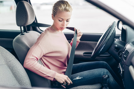 Safety first. Beautiful blonde caucasian lady fastening car seat belt.の写真素材