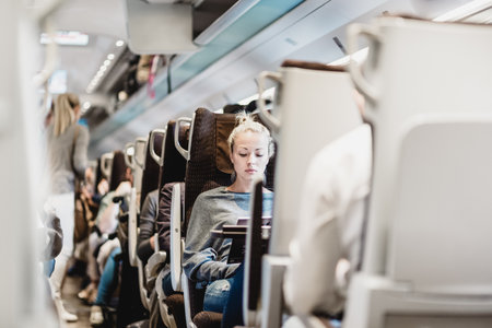 Blonde casual caucasian lady traveling by train. Train full of passengers going to work by public transport at rush hour.の写真素材