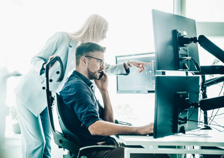 Stock broker business team trading online watching charts and data analyses on multiple computer screens in modern corporate work station office.の写真素材