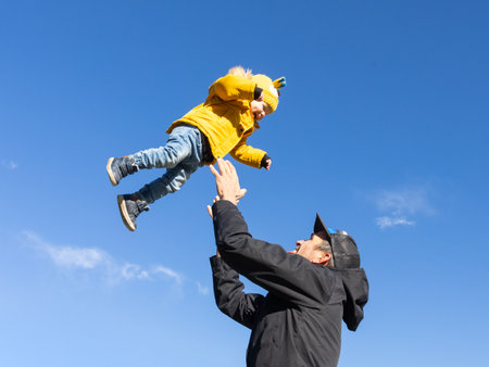 More, more,... dad, thats fun. Happy young father throws his cute little baby boy up in the air. Fathers Day, Father and his son baby boy playing and hugging outdoors in nature in fallの写真素材