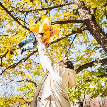 More, more,... dad, thats fun. Happy young father throws his cute little happy baby boy up in the air. Fathers Day, Father and his son baby boy playing and hugging outdoors in nature in fallの写真素材